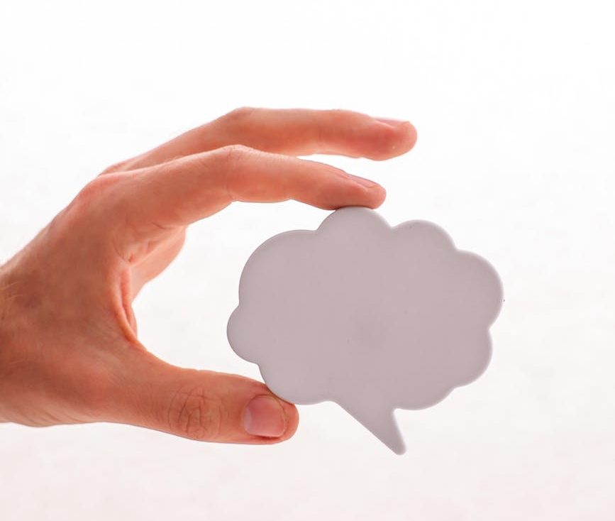 hand holding plastic cutout of thinking bubble